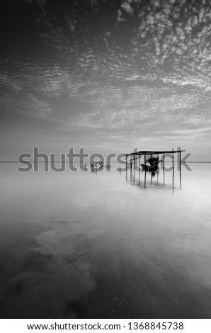 Fine art Black & white image of beautiful landscape of the beach at morning. Fisherman boat and clouds reflecting in the water. Long exposure. 