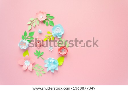 Easter egg made of paper flowers on pink background. Cut from paper.