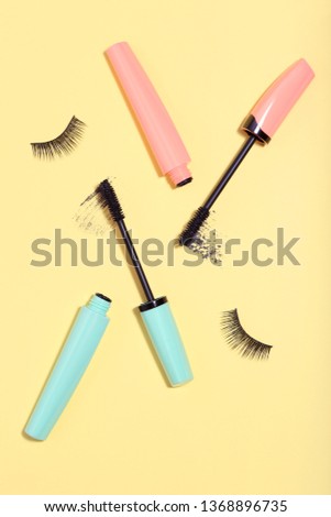 Makeup mascara with eyelashes on yellow background. Minimalism concept