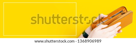 web banner design for woman fashion in spring and summer concept with beauty woman hand hold and open modern brown leather purse or wallet in left hand with yellow pastel background