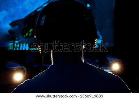 Men wearing headphones playing video games late at night