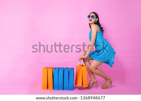 Full picture,Portrait of a happy Asian pretty girl holding shopping bags away isolated over pink background,colorful shopping concept.