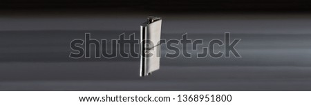 Stainless hip drinking flask isolated on silver reflective background with dead space.