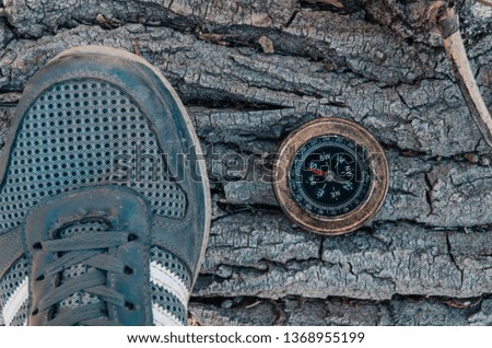 Old compass and shoes on a background of tree bark.