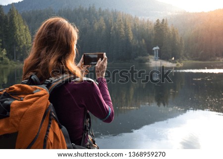 tourist girl making a photo shoot of  mountain lake synevyr. Carpathians,  Ukraine.

