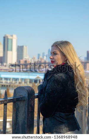 Beautiful blond girl looking at the New York city skyline in the sunshine weather. 