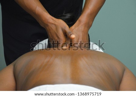 Black person getting a massage from a black masseur. Royalty-Free Stock Photo #1368975719