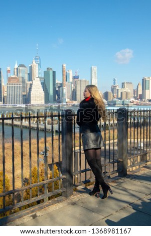 Beautiful blond girl looking at the New York city skyline in the black attire
