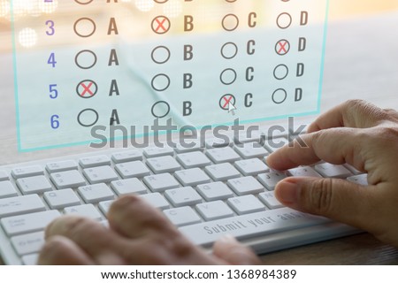 Dry hand of adult student using white keyboard on table to do test examination with multiple choice questions on virtual screen at home. Education futuristic technology and Lifelong learning concept.