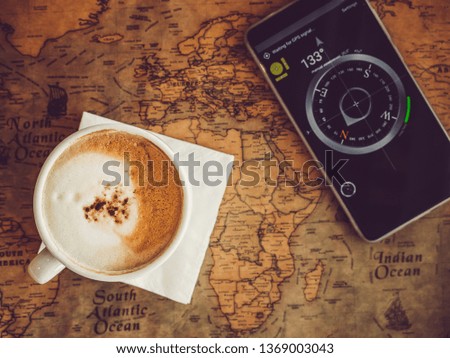 Old, vintage map and mobile phone with a picture of a compass. Top view, close-up. Concept of leisure and travel