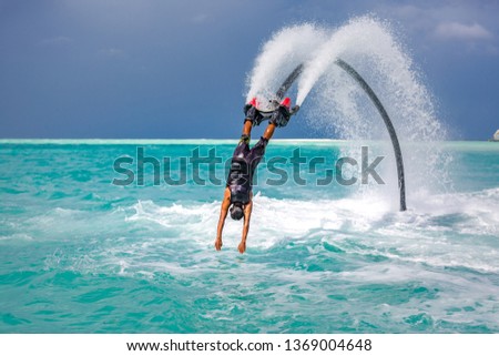Professional pro fly board rider in tropical sea, water sports concept background. Summer extreme sports, silhouette of a fly board rider at sea Royalty-Free Stock Photo #1369004648