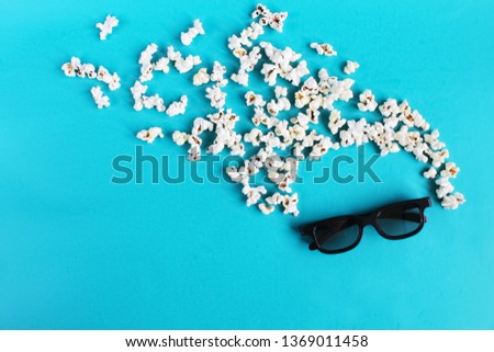 Cinema time on blue paper background. Abstract fun active image of viewer, 3D glasses, popcorn. Concept cinema movie and entertainment. Flat lay composition with copy space