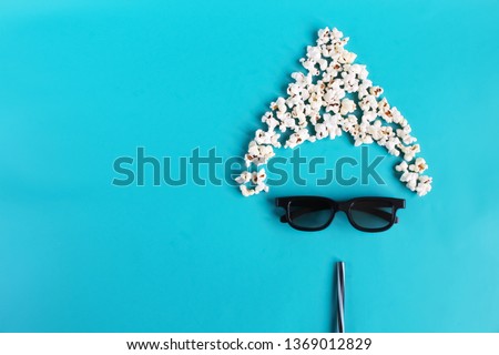 Cinema time on blue paper background. Abstract fun image of viewer, 3D glasses, popcorn. Concept cinema movie and entertainment. Top down composition with copy space