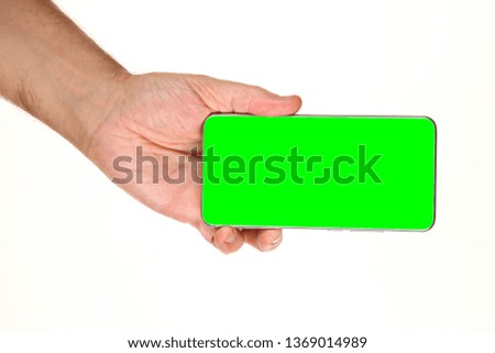 Human hand holds a modern smartphone with a blank chromakey screen in a palm. Technology and advertising concept. Detailed closeup studio shot isolated on abstract blurred white background