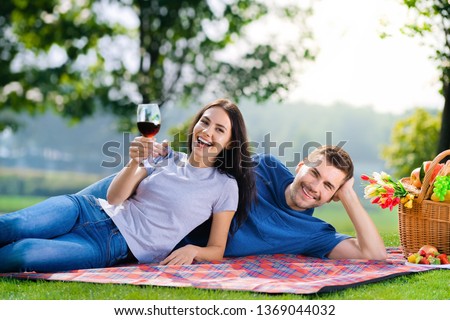 Bright photo of young couple in love, lying together on a picnic blanket, outdoors
