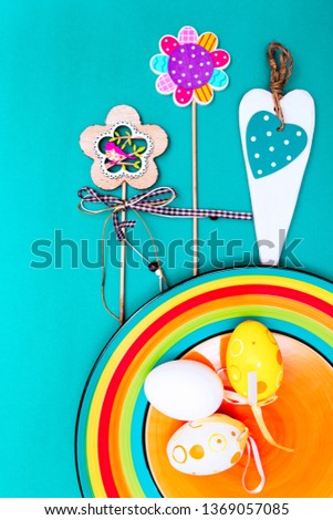 Easter composition with eggs, flowers, carrots and a rainbow on a blue turquoise background. Orange plate. Blue and turquoise background. Place for text. happy Easter. Happy Easter.