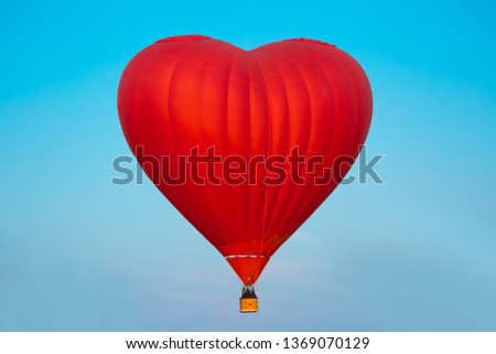 Love Balloon in the shape of a heart against the blue sky in flight, colorful cheerful entertaining mode of transport, flying in a balloon, concept of dreams and happiness. Red balloon aerostat. 