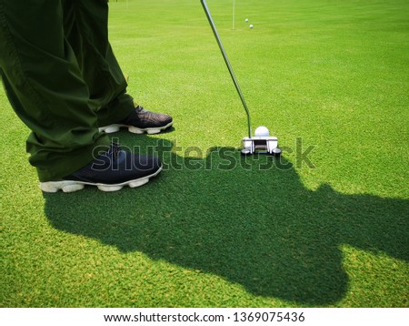 Golfer on training putt golf ball on the green