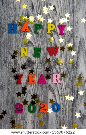 2020 Happy New year text for greeting card, with gold stars and colored letters on wooden background, calendar, invitation