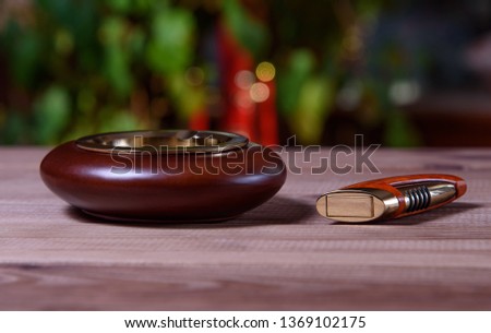 Stylish exquisite ashtray and lighters on a wooden table.