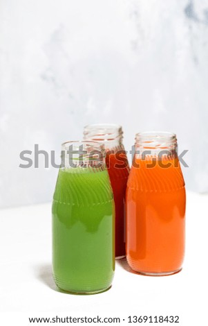 colorful vegetable juices in bottles on white background, vertical top view