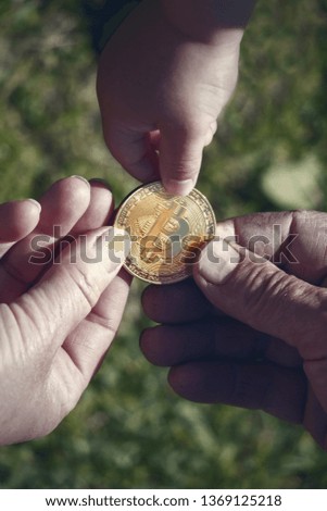 Hands of different people holding a gold coin bitcoin. Blurred background.