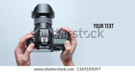 Female hands using digital camera on a gray background with copy space. Top view, minimalism. Royalty-Free Stock Photo #1369189097