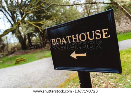 Black metal boathouse sign with gold lettering and directional arrow. Lough Rynn Estate, County Leitrim, Ireland.