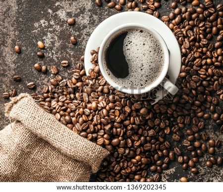 Coffee cup and coffee beans on dark stone background. 