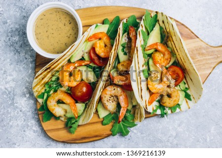 Seafood. Mexican food. Tortilla tacos with arugula, lemon, avocado and grilled shrimp pawns. On a light gray background. Top view copy space