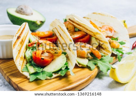 Seafood. Mexican food. Tortilla tacos with arugula, lemon, avocado and grilled shrimp pawns. On a light gray background. Top view copy space