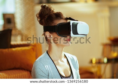 Closeup on relaxed active woman in sport clothes at modern home meditating in VR gear.