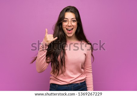 Teenager girl over purple wall making phone gesture. Call me back sign