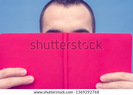 Male reads the book, visible only eyebrows, close up, copy space, for advertising, slogan, front view, blue background, toned