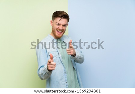 Redhead man over colorful background pointing to the front and smiling