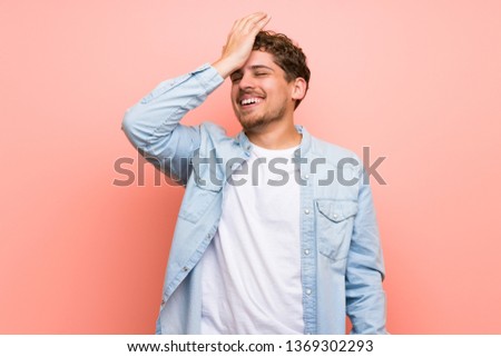 Blonde man over pink wall has just realized something and has intending the solution