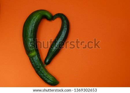 Ugly organic cucumbers shaped in a form of heart on orange background. Image with copy space, top view Royalty-Free Stock Photo #1369302653