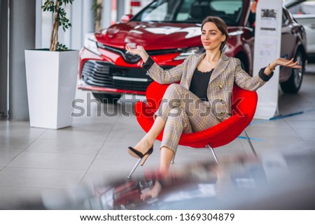 Female boss at a car showrrom sitting in a red chair