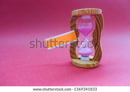 Blank note with sand clock for writing message on purple background