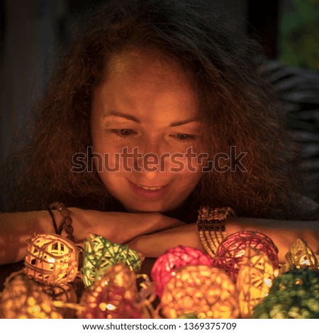 Beautiful young woman with colorful garlands of lights at home, close up portrait