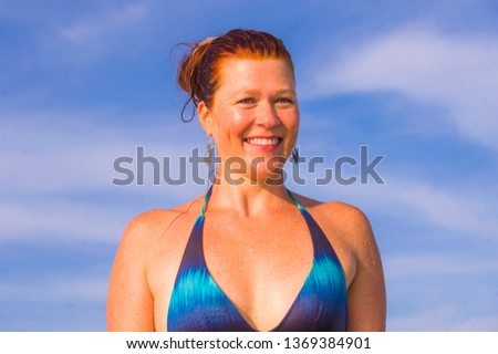 young happy and playful red hair woman in bikini swimming on the sea playing with big waves enjoying Summer holidays paradise beach relaxed and excited in travel destination and lifestyle concept