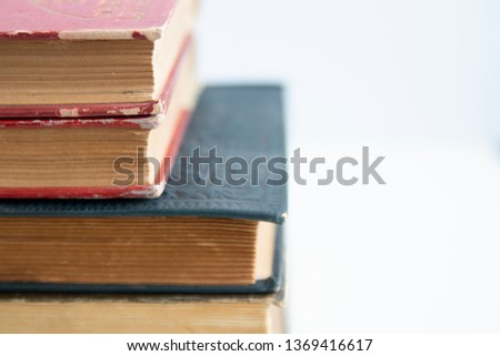 Old worn books stacked on white surface close up with copy space