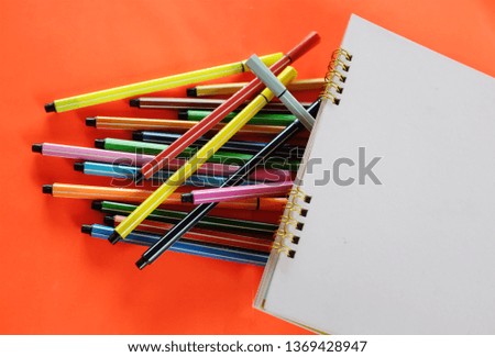 close up colorful pens ,notebook on an red background