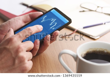 Stock market charts on smartphone screen.
Closeup of male hands holding smartphone. Checking financial market.
 Royalty-Free Stock Photo #1369435559