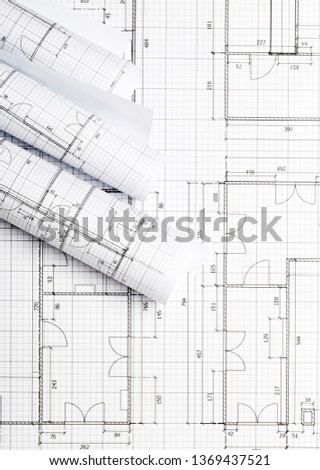 Rolls of architectural blueprint house building plans on blueprint background on table flatlay top view from above