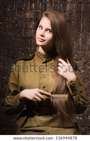 Soviet female soldier in uniform of World War II combs her hair