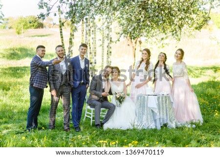 Wedding day bride and groom with bridesmaids and groomsmen posing in garden. wedding newlyweds couple with best friends. People drink champagne and hugging.