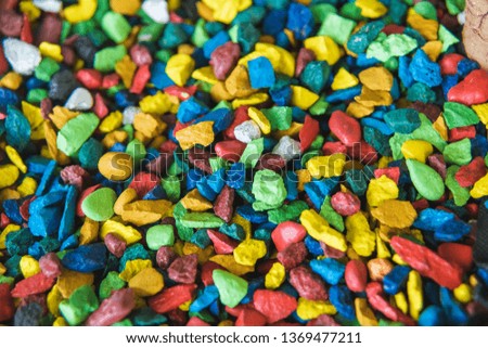 Multi-colored pebbles for garden decoration. Colored gravel in the park. Yellow, blue, red and green small stones. The texture of the gravel path.