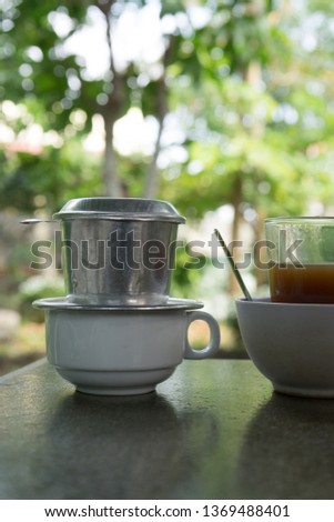 Vietnamese traditional coffee with drip filter (phin). The bean is grind and put in the filter with hot water. It will then drip coffee drops. The below cup will take the drops down within few minutes