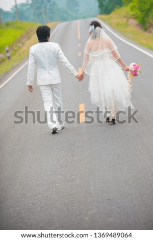 Wedding couple in wedding cloths walking along the road